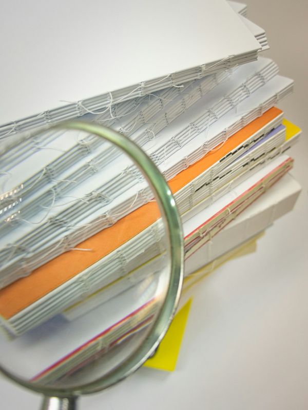 A magnifying glass held over a stack of files