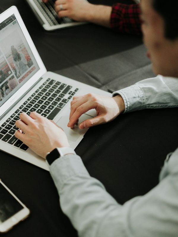 Hands typing on a laptop at a shared work table