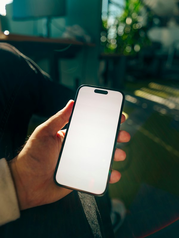 A hand holding a smartphone with a blank screen