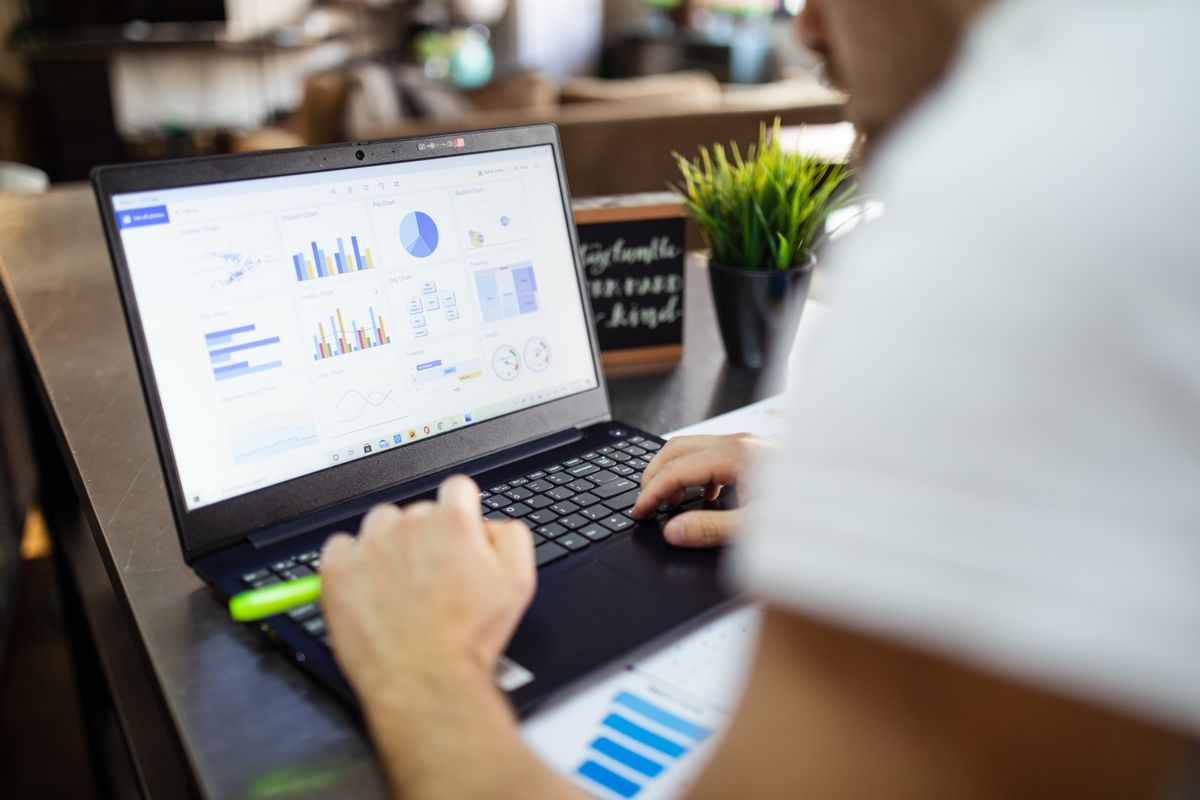 A person reviewing a dashboard of charts and graphs on a laptop